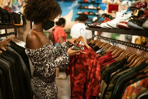 Stylish woman in a mask browses fashionable clothes at a boutique store.